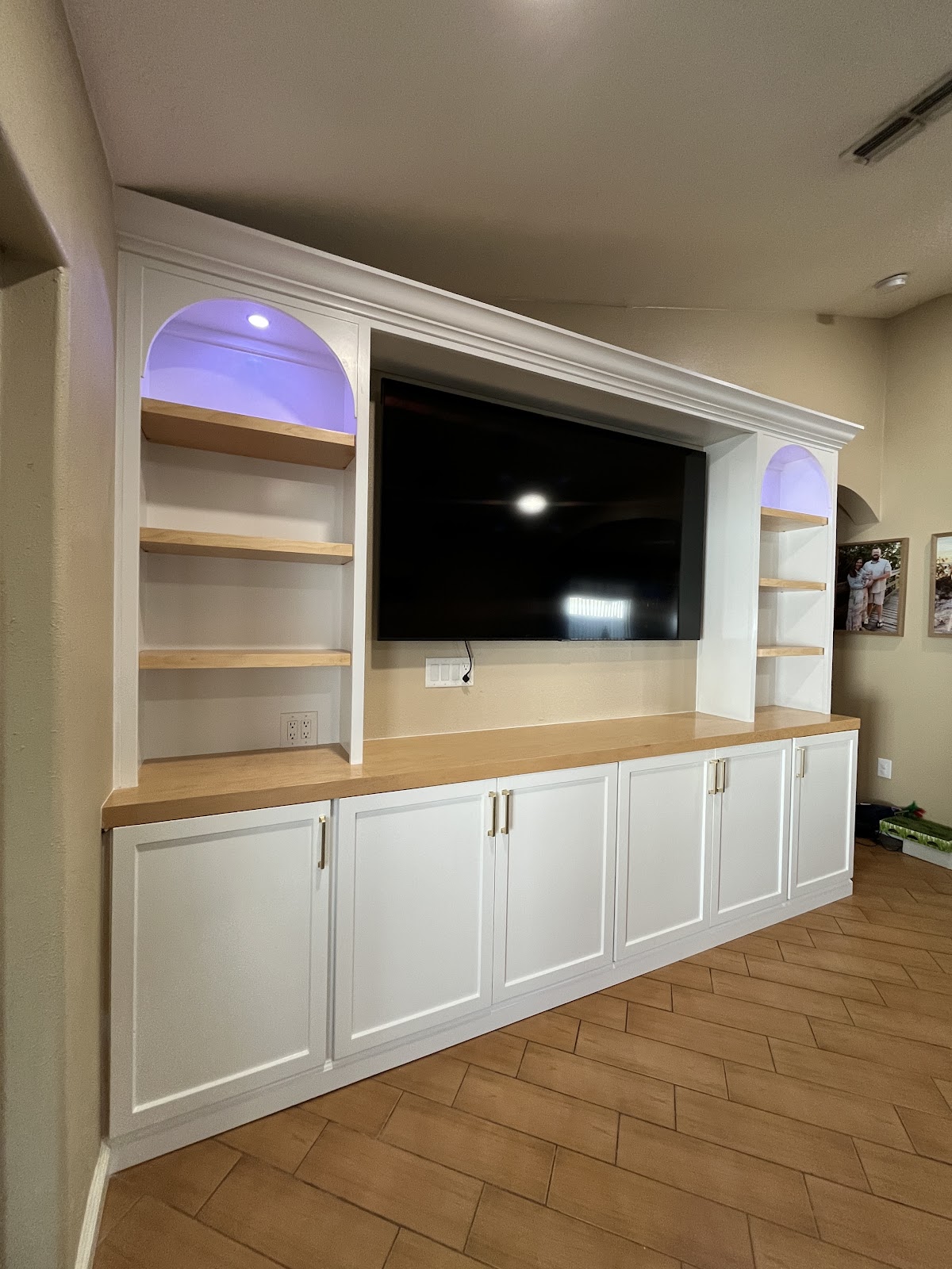 White built-in media cabinetry with arched shelves and wood accents