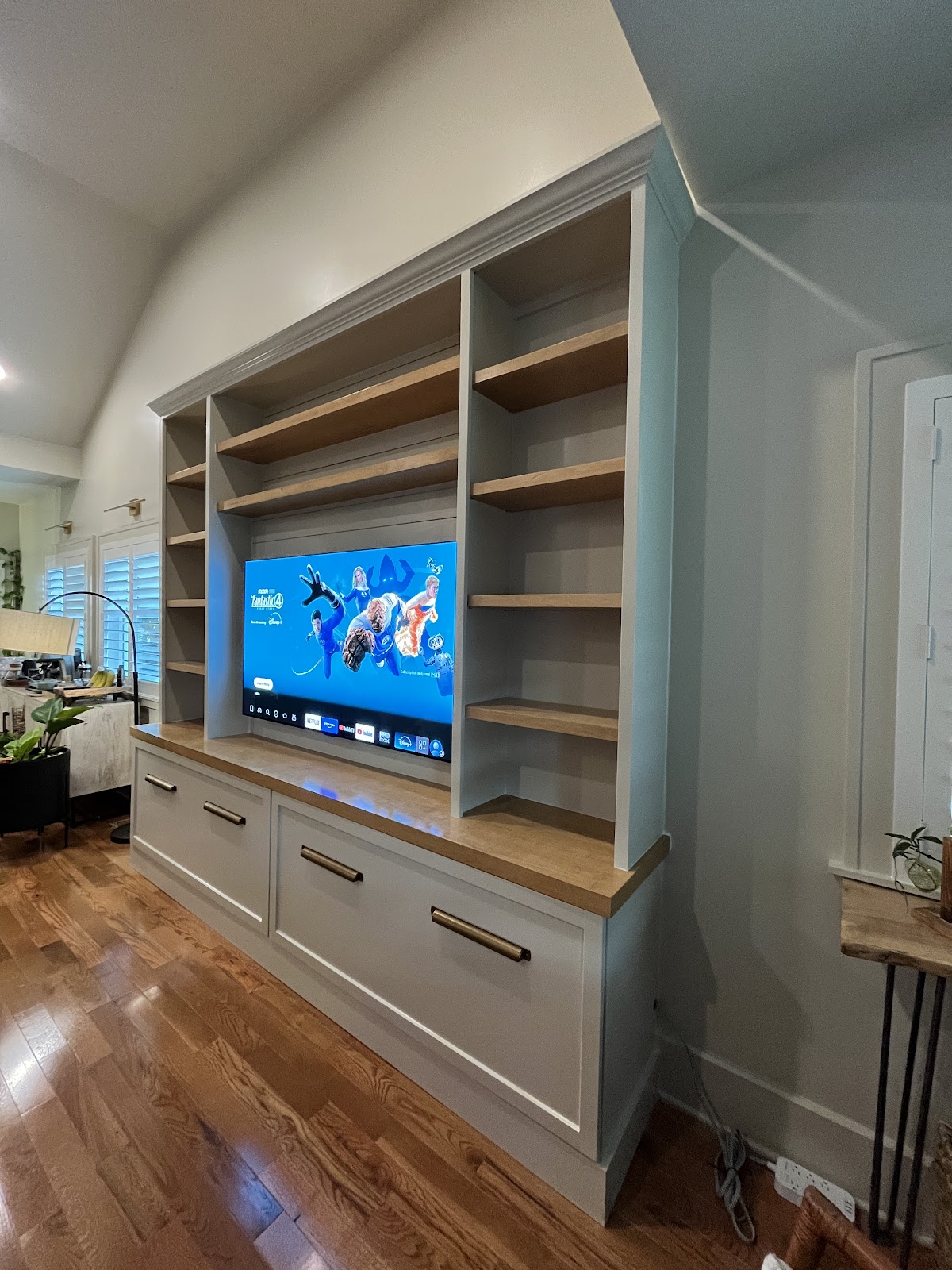 Gray entertainment built-in with wood shelves and large drawers