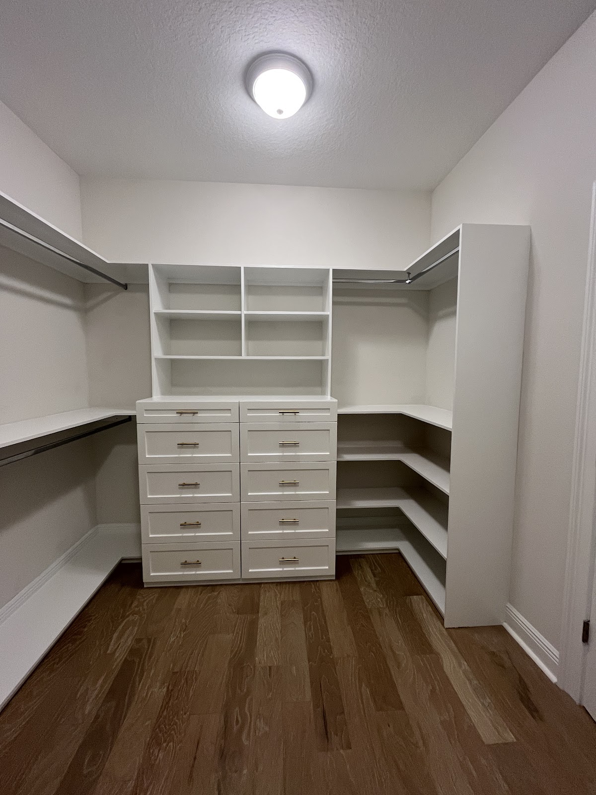 Custom white closet storage with drawers and hanging rails