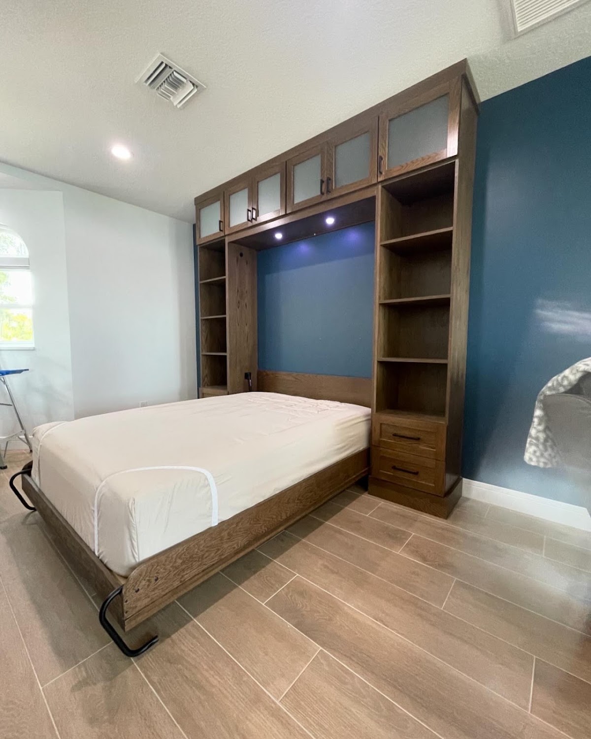 Wood Murphy bed open beneath custom surrounding cabinetry