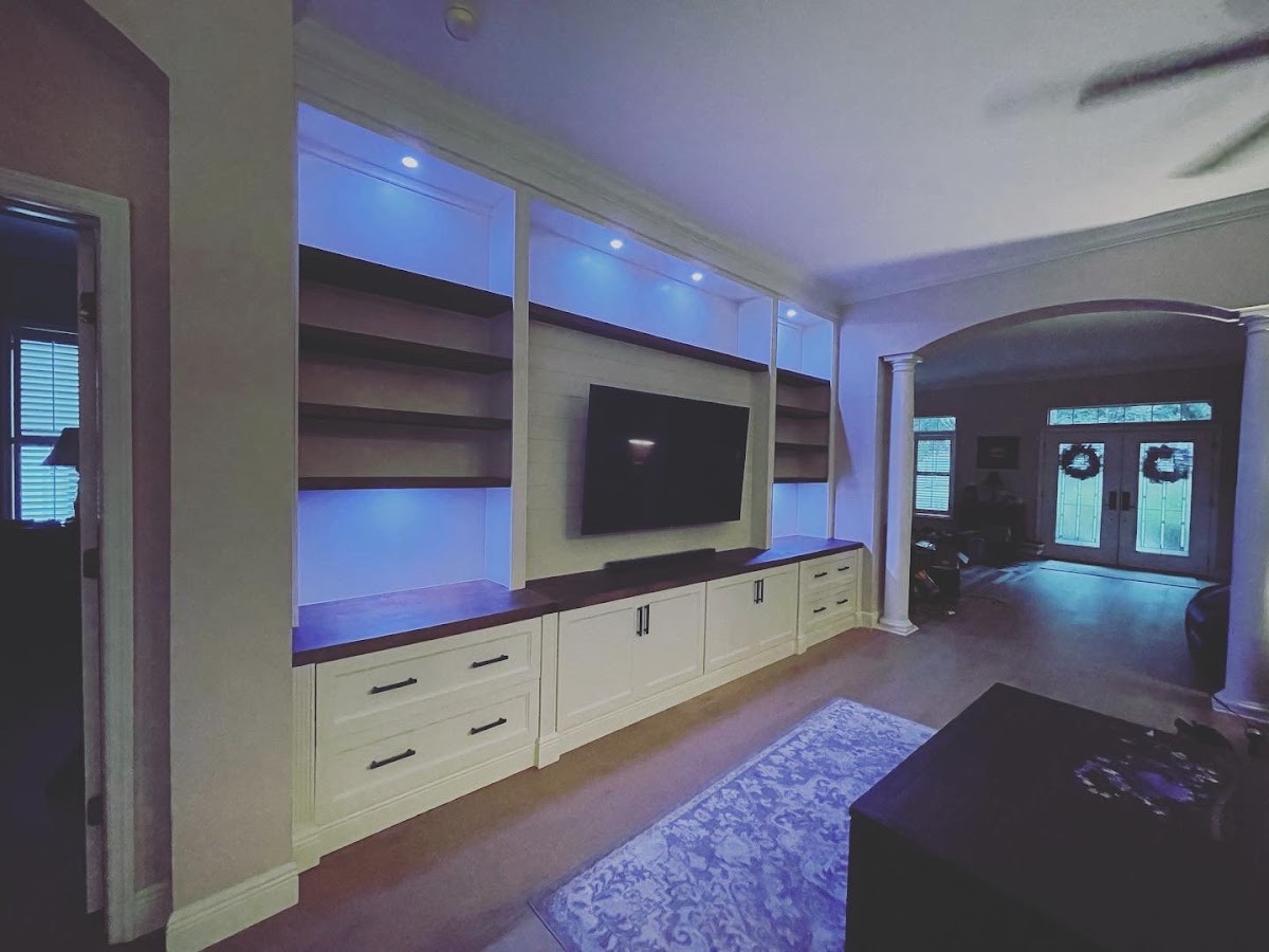 Wall-length white entertainment cabinetry with illuminated shelves
