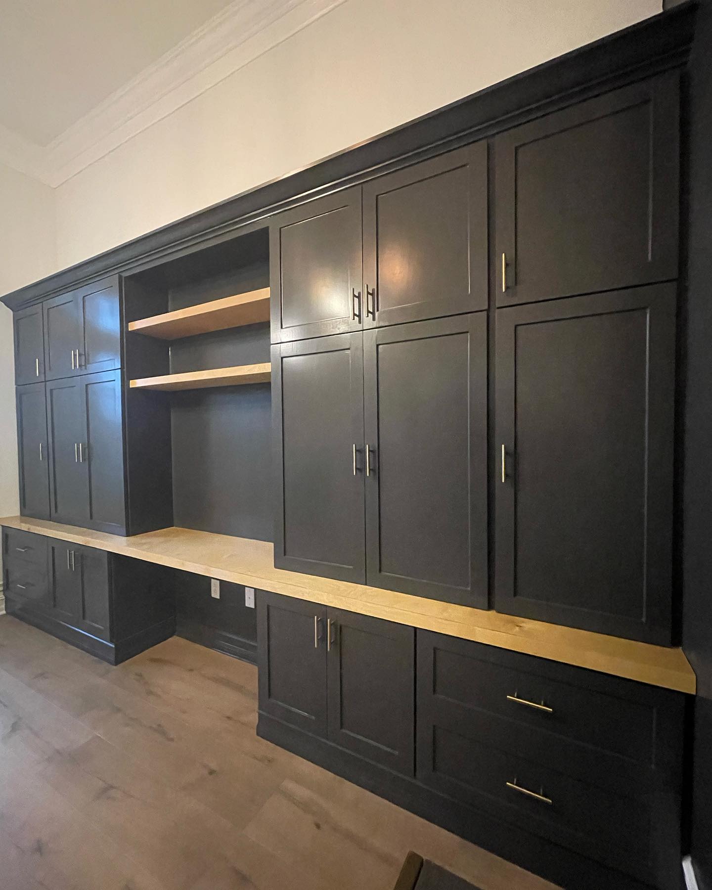 Dark custom cabinetry with wood countertop and brass-colored handles